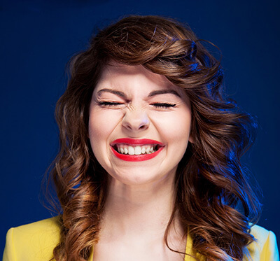 Woman shutting her eyes closed tightly and smiling.