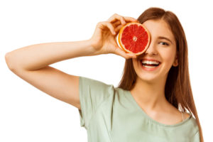 Girl holding a grapefruit over her right eye.