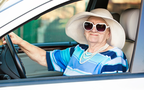 Older woman behind the wheel wearing sunglasses and a hat