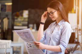 Young woman with glasses reading a newspaper