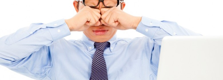 Man rubbing his eyes while working.