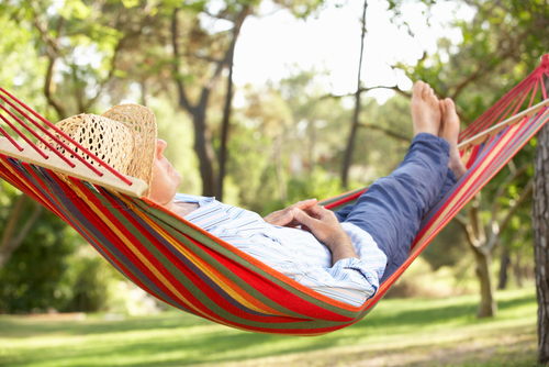 A man with a straw hat laying in a hammock